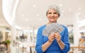 Senior woman with dollar money over shopping mall