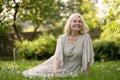 Senior woman in dress sitting on grass at the park Royalty Free Stock Photo