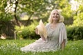 Senior woman in dress sitting on grass at the park Royalty Free Stock Photo