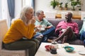 Senior woman drinking coffee while multiracial friends talking in background at home Royalty Free Stock Photo