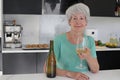Senior woman drinking white wine in the kitchen Royalty Free Stock Photo