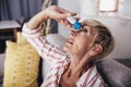 Senior woman dripping some medicine with dropper on her eyes