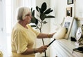 Senior woman dusting a family photo frame Royalty Free Stock Photo