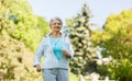 Senior woman with earphones running in summer park Royalty Free Stock Photo