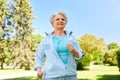 Senior woman with earphones running in summer park Royalty Free Stock Photo