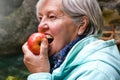 Senior woman eating apple outside in the park