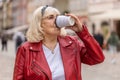 Senior woman enjoying drinking morning coffee hot drink, relaxing, taking a break in city street Royalty Free Stock Photo
