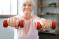 Senior woman exercise at home sitting on exercise ball with dumbbells in front blurred Royalty Free Stock Photo