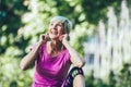 Woman exercising in park while listening to music. Mature woman resting after exercise Royalty Free Stock Photo