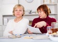 Senior woman explaining document to offended female Royalty Free Stock Photo