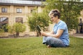 Senior woman in eyeglasses reading book while sitting on grass in park and having a rest Royalty Free Stock Photo