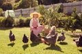 Senior woman farmer feeding her free range chickens