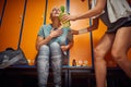 Senior woman feeling sick from working out, sitting in changeroom, young woman helping her holding water bottle Royalty Free Stock Photo