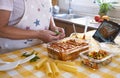 The senior woman finishes preparing a pan with homemade stuffed cannelloni ready for the oven. Ingredients around her Royalty Free Stock Photo