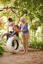 Senior woman, garden and grandma pushing her grandchildren on a tyre swing or holidays and having fun in summer. Excited Royalty Free Stock Photo