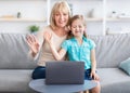 Senior woman and girl having videocall using laptop waving hands Royalty Free Stock Photo