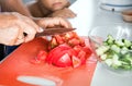 Senior woman grandmother cooking healthy salad for grandson. Grandma cutting tomato by knife on cutting board for dinner