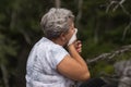 Senior woman with gray curly hair has season allergy and runny nose, sneezing.