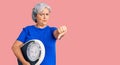 Senior woman with gray hair holding weight machine to balance weight loss with angry face, negative sign showing dislike with