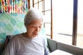 Senior woman with gray hair sitting on a reclining nursing bed and staring at a table