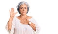 Senior woman with gray hair wearing bohemian style swearing with hand on chest and open palm, making a loyalty promise oath