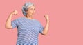 Senior woman with gray hair wearing casual striped clothes showing arms muscles smiling proud