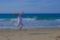 Senior woman with greay hair and a white dress jumping in the air at the beach Royalty Free Stock Photo