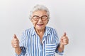Senior woman with grey hair standing over white background excited for success with arms raised and eyes closed celebrating Royalty Free Stock Photo