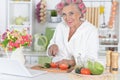 Senior woman in hair rollers cutting vegetables on kitchen Royalty Free Stock Photo
