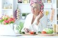 Senior woman in hair rollers cutting vegetables on kitchen Royalty Free Stock Photo