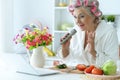 Senior woman in hair rollers singing karaoke with laptop Royalty Free Stock Photo