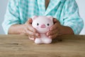 Senior woman hand covering piggy bank