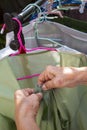 Senior woman hands dry green clothes in the sun with Colourful plastic clothes hang on stainless steel clothes rack