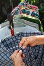 Senior woman hands dry plaid clothes in the sun with Colourful plastic clothes hang on stainless steel clothes rack