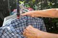 Senior woman hands dry plaid clothes in the sun with Colourful plastic clothes hang on stainless steel clothes racke