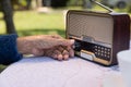 Senior woman hand turning knob on vintage radio in backyard