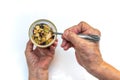 Senior woman hands using spoon ladling mixed Nuts, Macadamia, Dried fruits, Sunflower seeds, Raisins in plastic can on white Royalty Free Stock Photo