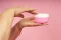 Senior woman hands applying cream on hands on coral background