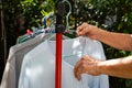 Senior woman hands dry blue clothes in the sun with Colourful plastic clothes hang on stainless steel clothes rack