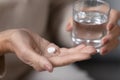Senior woman hands holding pill and glass of water closeup Royalty Free Stock Photo