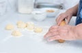 Senior woman hands rolling out the dough with a rolling pin on a white kitchen table with blurred grated apple and sugar Royalty Free Stock Photo