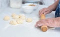 Senior woman hands rolling out the dough with a rolling pin on a white kitchen table with blurred grated apple and sugar Royalty Free Stock Photo