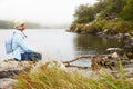 Senior woman with a hat sitting by the lake, admiring the view Royalty Free Stock Photo