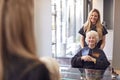 Senior Woman Having Hair Cut By Female Stylist In Hairdressing Salon