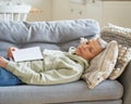 Senior woman having a nap on sofa, fell asleep after reading book at home Royalty Free Stock Photo