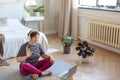 Senior woman in headphones having video conversation with a trainer online before a Pilates workout.