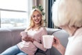Senior woman and her attractive daughter spending time together at home. Sitting on sofa and drinking tea together. Happy Mothers Royalty Free Stock Photo
