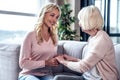 Senior woman and her attractive daughter spending time together at home and sitting on sofa. Happy Mothers` Day Royalty Free Stock Photo