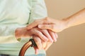 Senior woman with her caregiver at home. Old hands and young hands on cane close up. Concept senior people health care. Royalty Free Stock Photo