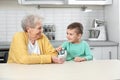 Senior woman with her grandson using digital glucometer at home Royalty Free Stock Photo